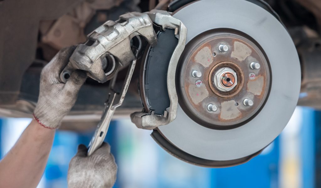 Replacing brake pads in the service center Car mechanic wearing white gloves, is about to change car brake pads